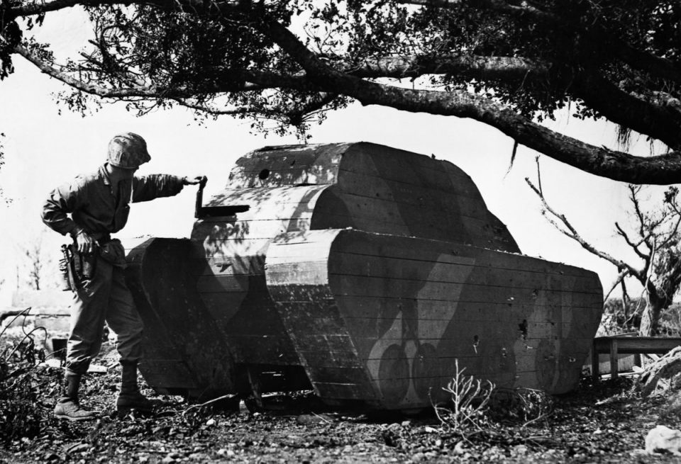 1945г. Морской пехотинец армии США осматривает деревянную планку в муляже японского танка на Окинаве.